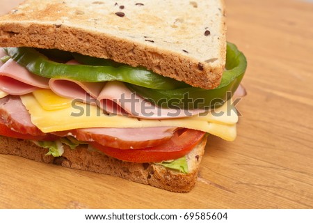 meat, lettuce , cheese and vegetables big sandwich on toasted whole wheat bread
