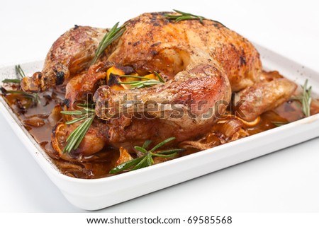 whole roasted stuffed chicken in a dish on white background