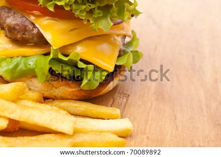 french fries and big double cheeseburger on a wooden table