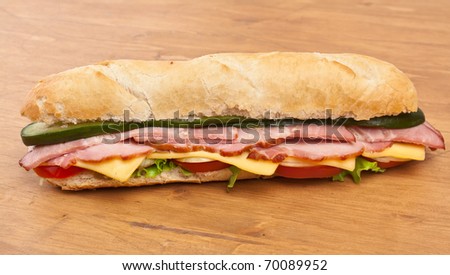 long baguette sandwich with lettuce, vegetables, ham, bacon and cheese