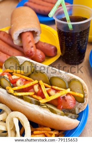group of tasty hot dogs with mustard and ketchup on  plates and cola on a table