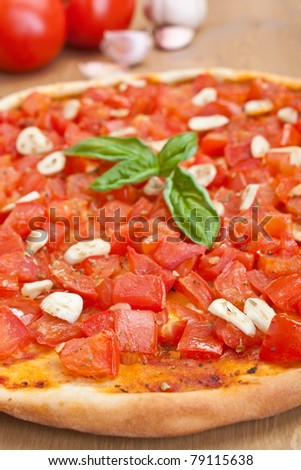 thin-crust pizza alla marinara with tomatoes and garlic and ingredients on a table