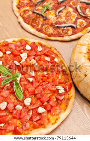 group of three pizzas: alla marinara with tomatoes and garlic, alla napoletana with anchovies, mozzarella and tomato sauce and chicago-style deep- dish stuffed pizza