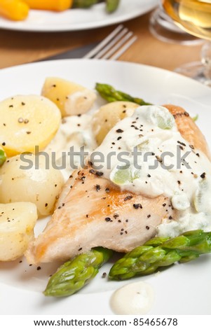 Baked chicken with creamy asparagus sauce served with potatoes and carrots