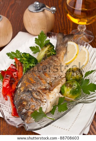 Dorado fish garnished with vegetables, herbs and lemon  on a dish