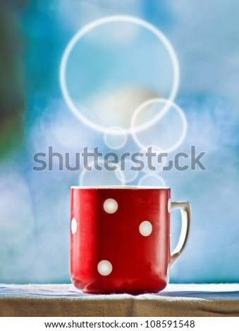 Red cup of coffee with dream smoke on blue background