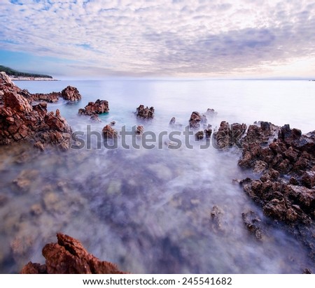 Beautiful sunset at romantic tropical beach cove with stones and water in motion