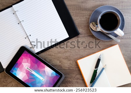 Digital tablet computer with sticky note paper and cup of coffee on old wooden desk. Simple workspace or coffee break with web surfing.