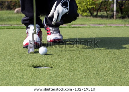 Low section of man\'s feet with golf club and ball
