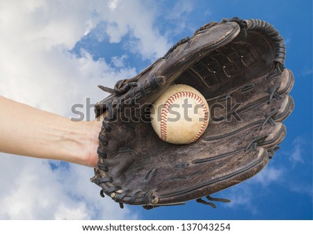 person catching baseball in leather baseball glove on blue sky