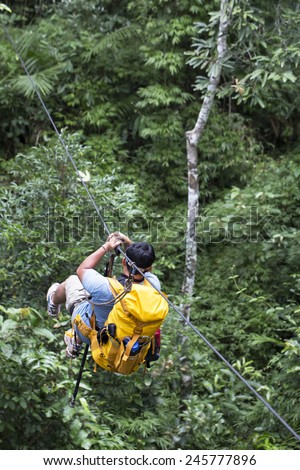 A man ziplines through the forest in Lao