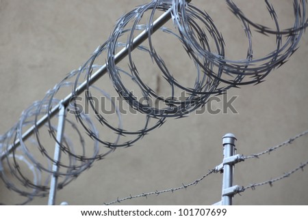 RAZOR WIRE - Medium view of razor wire running above barbed wire fence.