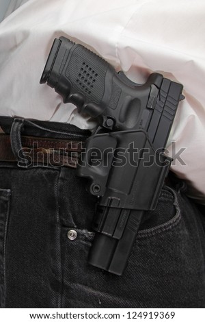 Pistol Packing/close up of holstered handgun against plain white shirt & black denim