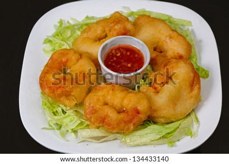 Battered Chinese shrimp arranged on bed of lettuce with chile sauce in center
