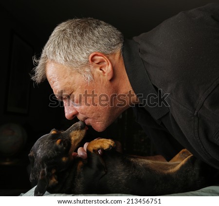 Middle age man having his face licked by short hair brown & black dachshund