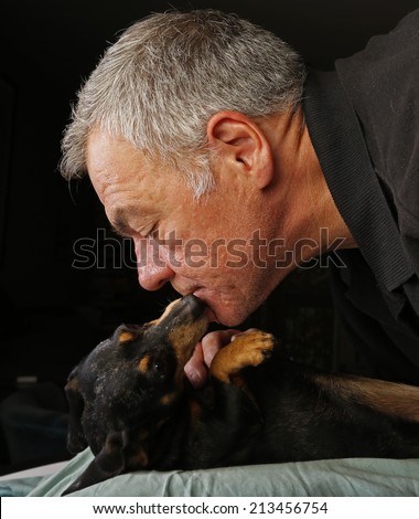 Middle age man accepting kisses from short hair black & brown dachshund