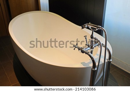 Elegant stand-alone bathtub in white ceramic with stainless steel faucet & fixtures