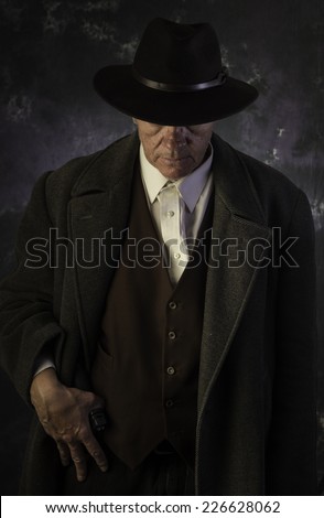 American Gunner Series/Middle age man in overcoat & fedora standing with handgun against portrait background