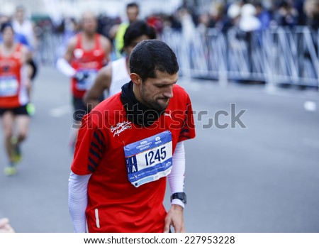 NEW YORK CITY - NOVEMBER 2 2014: the 43rd annual New York City Marathon saw more than 50,000 entrants run through all five boroughs. Male runner pauses with leg cramp on 59th Street close to finish