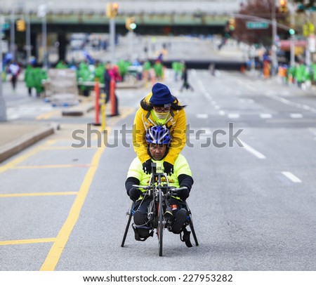 NEW YORK CITY - NOVEMBER 2 2014: the 43rd annual New York City Marathon saw more than 50,000 entrants run through all five boroughs. Volunteer gets ride with wheelchair division in Sunset Park