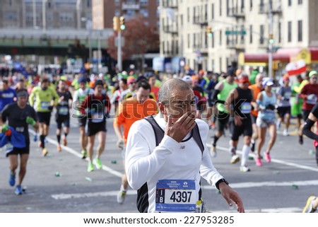 NEW YORK CITY - NOVEMBER 2 2014: the 43rd annual New York City Marathon saw more than 50,000 entrants run through all five boroughs. Male runner wipes his face along mile four in Sunset Park, Brooklyn