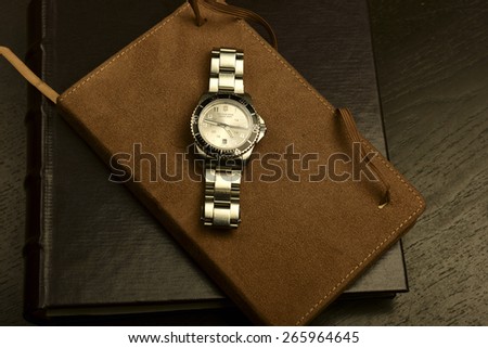 NEW YORK CITY - APRIL 1 2015: Victorinox Swiss Army Watch with trademark black enamel unidirectional bezel atop suede-bound book