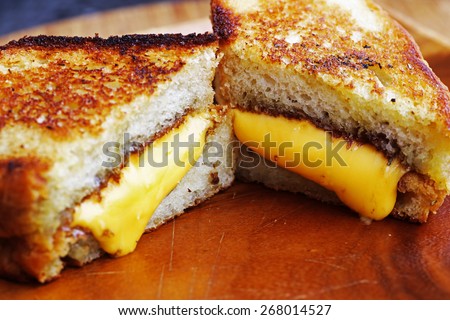 Grilled cheese sandwich made with cheddar and thick rosemary bread on wood serving platter