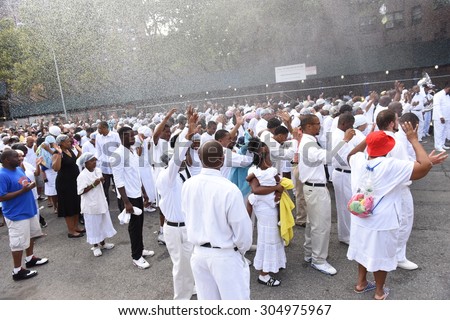 NEW YORK CITY - AUGUST 9 2015: members of the United House of Prayer for All People gathered along 116th Street in Harlem to be baptized in the church's annual tradition that uses fire hoses