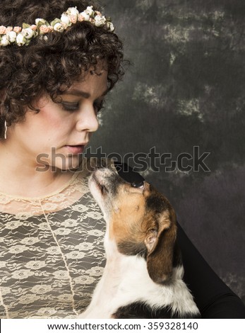Pals/Pretty, stylish young woman looking down at small, mixed-breed dog as dog looks up at her against portrait background