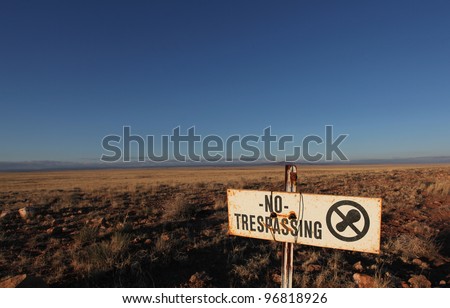 No Trespassing on US 40/Worn no trespassing sign against desert & blue sky background along US 40 in Arizona