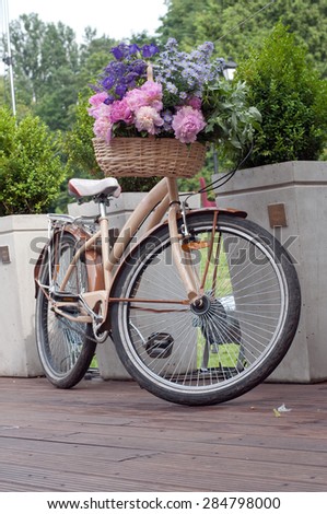 Bicycle with flower basket  waiting near flowerbed.