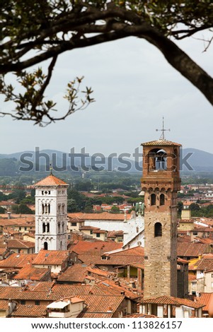 View on two towers of the city of Lucca in Tuscany, Italy, from underneath the trees on top of the Guinigi tower