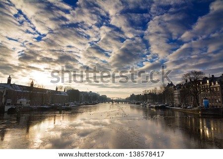 Beautiful winter panorama of the river Amstel in Amsterdam, the Netherlands, looking towards the skinny bridge.