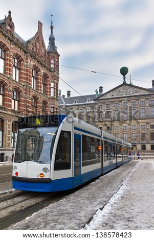 Tram in Amsterdam, the Netherlands, with the Magna Plaza and the Royal Palace in winter
