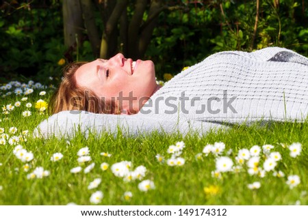 Beautiful woman lying in the garden in a a field with daisies in spring