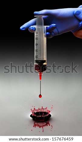Art concept of a big syringe dripping blood into water