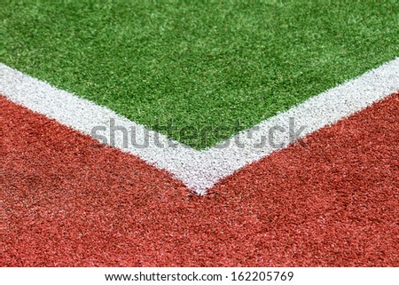 An Artificial Turf sportsfield detail image with green, red and white lines