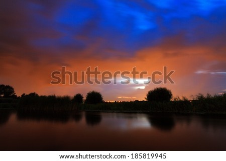 A dark colored ominous sky at the river at night in the Netherlands