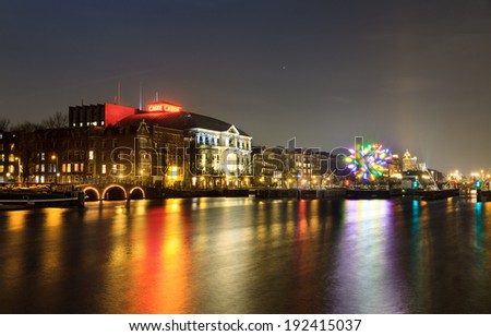 AMSTERDAM, THE NETHERLANDS - DECEMBER 18, 2013: Night view of the river Amstel looking towards theater \'Carre\' with a piece of art in the river in Amsterdam, The Netherlands, on December 18, 2013