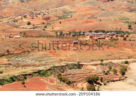Small village and rice fields in the damaged red landscape of Madagascar