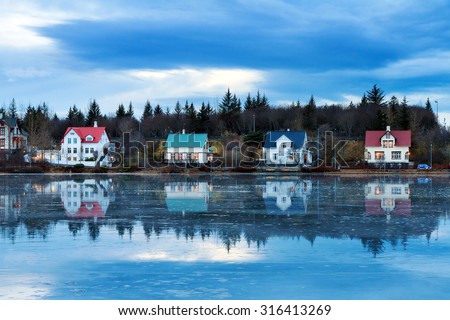 Beautiful houses reflected in lake Tjornin in Reykjavik Iceland, during the blue hour in winter