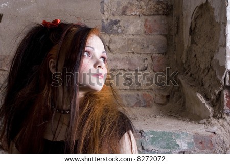 The attractive girl in Gothic style on a background of a brick wall