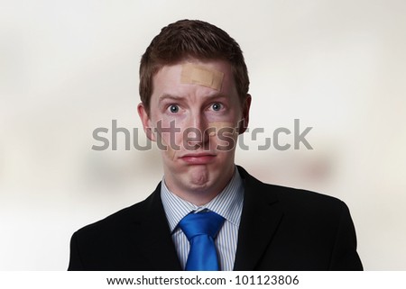 businessman with plasters on his face looking hurt and unhappy
