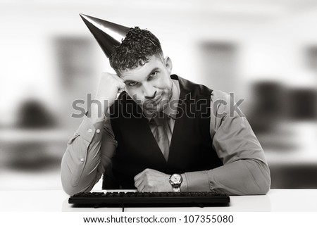businessman wearing a party hat sitting at his desk