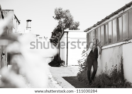 woman waiting for someone standing by a wall down a side street