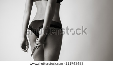 sexy woman with her back to camera in underwear hands down by her side in one hand she is holding a knife
