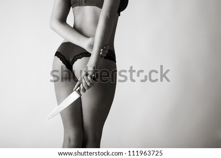 sexy woman with her back to camera in underwear hands down by her side in one hand she is holding a knife
