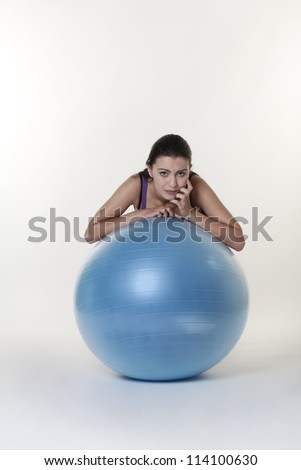 woman looking over gym ball a bit unsure about something