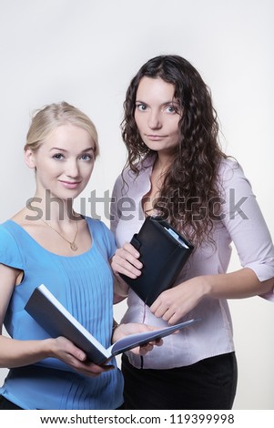 two work colleagues looking over something in a large note book