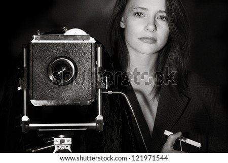 black and white image of a young woman taking a photography with a large 5x4 film camera